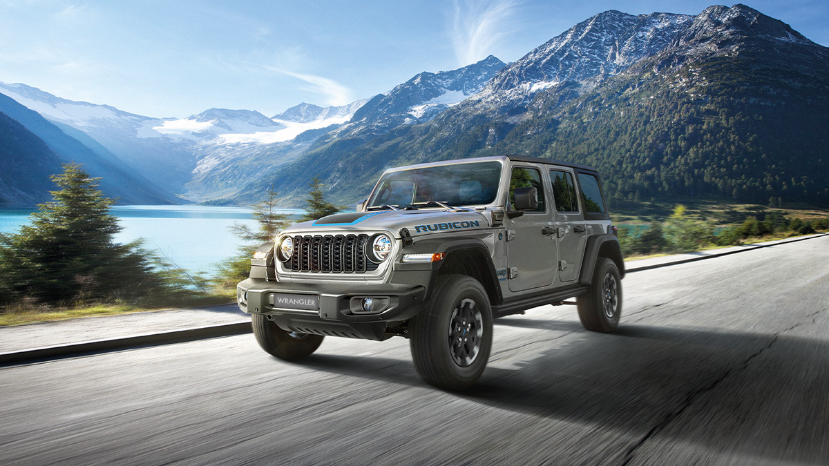 Jeep Wrangler auf einer Strasse vor einem See in den Bergen