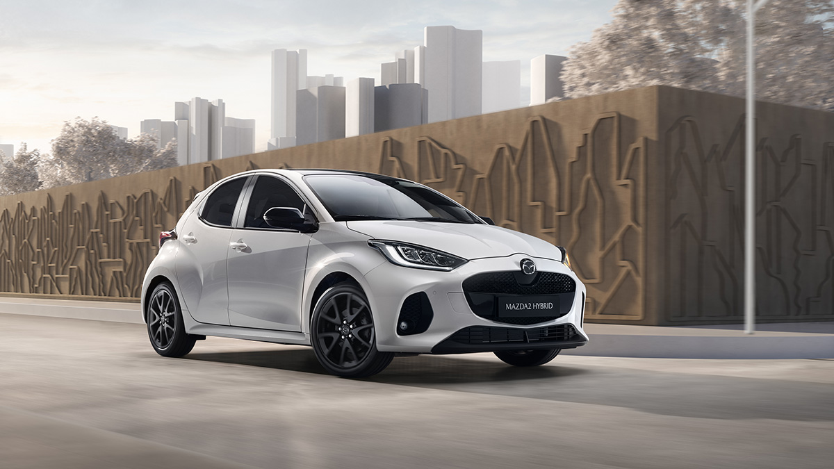 Der Mazda 2 Hybrid vor Bäumen auf einer Strasse